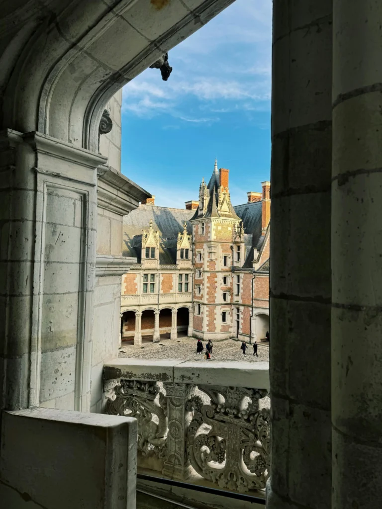 Vue sur la cour intérieure du Château royal de Blois depuis une galerie, mettant en valeur l’architecture Renaissance et les façades en pierre et brique.