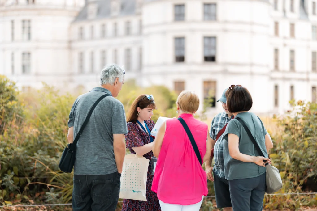Guide indépendante échangeant avec un petit groupe de visiteurs lors d’une visite guidée devant le château de Chambord